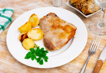 Service plate containing grilled pork and fried potatoes with necessary table laying