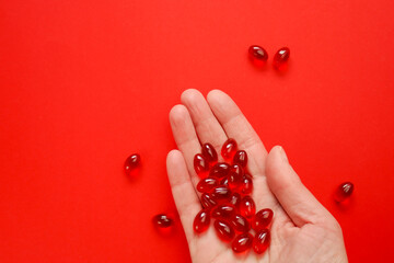 Krill oil capsules in a hand on a red background .omega fatty acids.Healthy eating and food...