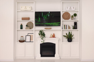 TV, fireplace and shelves with different decor in room. Interior design