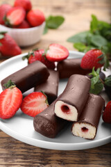 Delicious glazed curd snacks with fresh strawberries and mint on wooden table