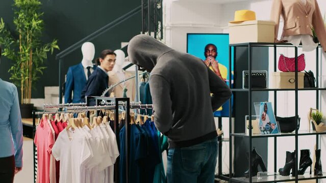 Thief trying to stole trendy clothes from modern boutique, being caught by asian bodyguard. African american couple arguing with store worker and security guard, trying to escape crime accusation