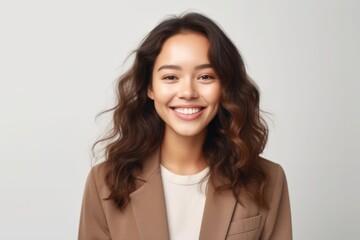 Fototapeta premium smiling young asian businesswoman in beige suit looking at camera