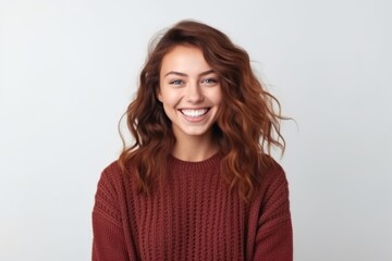 Portrait of a smiling young woman in sweater looking at camera over white background