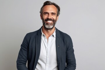 Obraz premium Portrait of a handsome mature man smiling and looking at camera over gray background