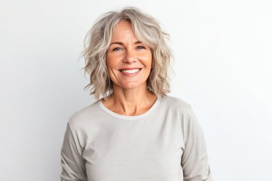 Portrait of smiling mature woman with grey hair against white background.