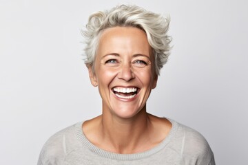 Fototapeta premium Portrait of a happy middle-aged woman laughing against white background