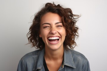 Close up portrait of a beautiful happy young woman laughing on gray background