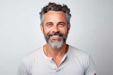 Portrait of a handsome mature man smiling at the camera while standing against grey background