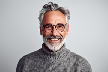 Portrait of a smiling senior man in eyeglasses looking at camera isolated on a gray background