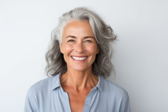 Portrait of smiling mature woman with grey hair looking at camera over white background