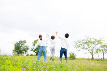 若い日本人ファミリーの後姿　新緑の公園で撮影