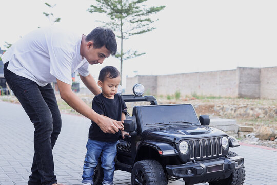 Father having fun with his son playing with big toy car at the park