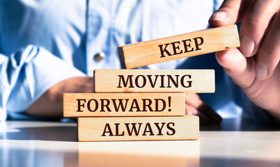 Close up on businessman holding a wooden block with a "Keep moving forward, always" message