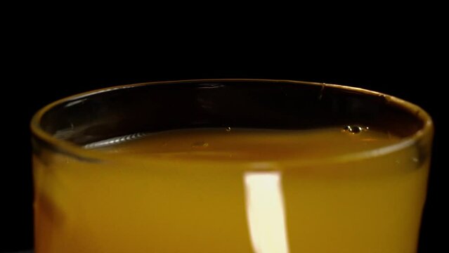 ice qube falling into orange juice glass with a black background