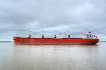 Photo of a large red cargo ship sailing across the waters of Argentina