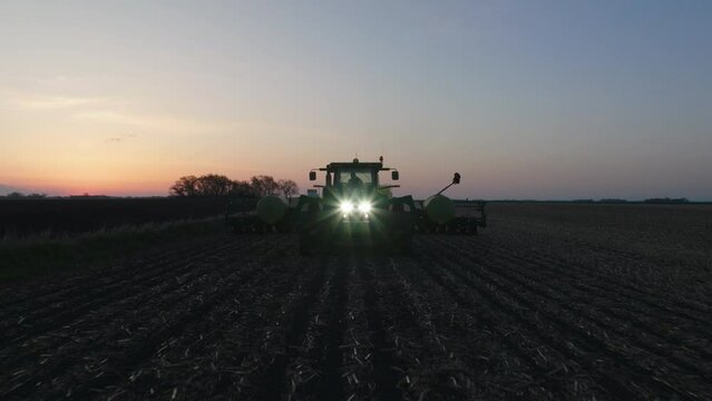 Aerial, tractor with strip till toolbar plowing farm field in the morning to prepare for seed planing