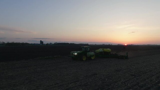 Aerial, tractor with strip till toolbar plowing fresh farm field in the morning
