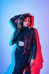 Fashion portrait of a black woman in a fashionable outfit shot in a studio with colorful lighting.