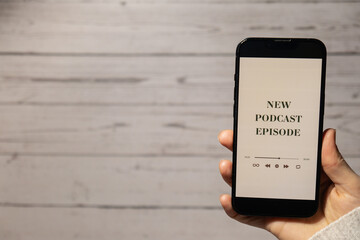 Unrecognizable woman holding mobile phone NEW PODCAST EPISODE listening website page app...