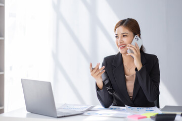 Cheerful business Asian student woman freelancer making telephone call share good news about project working in office workplace, business finance concept.	