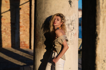 Obraz premium Outdoor portrait of a young blonde woman on city street. Sexy woman walking outdoors. Sensual girl posing on street. Fashion model posing on city. Street style summer trend. Fashionable sexy woman.