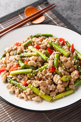Stir-fry asparagus with minced pork, sesame and chili pepper closeup on the plate on the table. Vertical