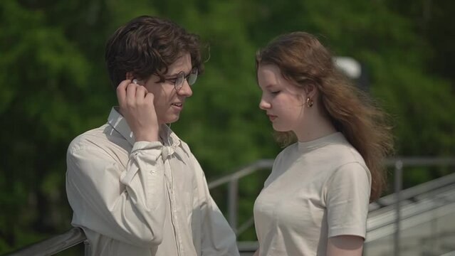 A teen boy shares headphones with a teen girl while listening to their favorite lyric song. first relationship. two teenagers are smiling. slow motion video. High quality Full HD video recording