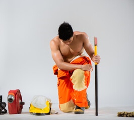 Attractive topless firefighter exudes a sense of calm and readiness as he sit and kneel down on a...