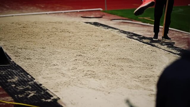 An athlete performs a long jump with a landing in a sandbox. Athletics championships. An athlete competes in the long jump.