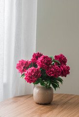 Bouquet of peonies in a ceramic vase on a wooden table