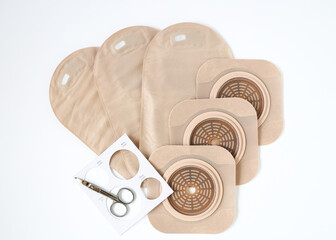 Two piece ostomy appliance including flange, pouch, measuring guide and scissor isolated a a white background
