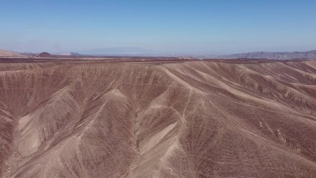 Video of the Palpa Lines near the famous Nazca lines. Drone rises in altitude revealing the flat plateau atop the mountain range. On the top are ancient long line geoglyphs. Located in Pampa, Peru.