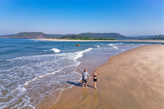 couple walking on beach aerial landscape of coastline and a beach seascape view drone Goa - Powered by Adobe