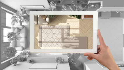 Augmented reality concept. Hand holding tablet with AR application used to simulate furniture and design products in total white background, urban jungle living room, top view