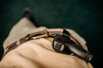 a concealed weapon in a holster behind his belt, - obrazy, fototapety, plakaty