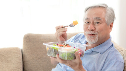 Lifestyle senior man feel happy enjoy eating diet food fresh salad on sofa