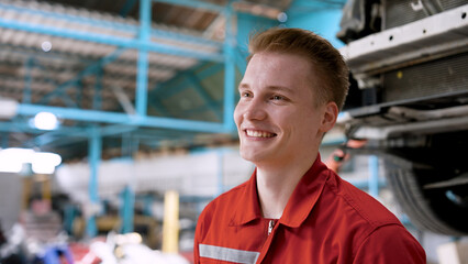 Caucasian male mechanic working in a garage, men in mechanic clothes standing smiling happily After inspecting every vehicle in the garage until it is ready to be returned to the customer.