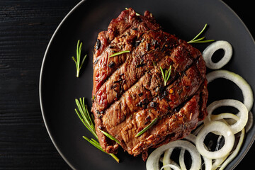Grilled ribeye beef steak with rosemary and marinated onion.
