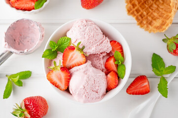 Strawberry ice cream with fresh berries in a bowl on a white wooden background. Selective focus