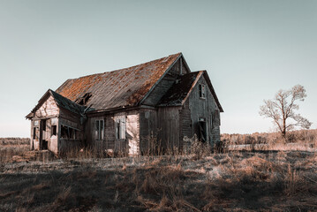 Abandoned 19th century house in a rural field at summer.Creepy summer evening.Toned.