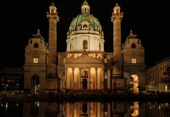 Facade of St- Charles Church at night in Vienna with reflection on water upfront