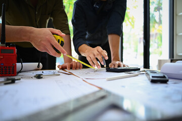 Team of architects discussing on project, working on construction plans together at co working space in office