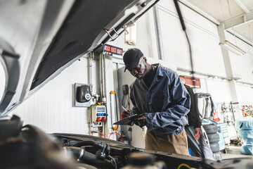 Obraz na płótnie Canvas Mechanics checking car engine under the open hood . High quality photo