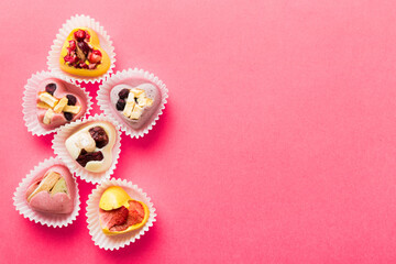chocolate sweets in the form of a heart with fruits and nuts on a colored background. top view with space for text, holiday concept