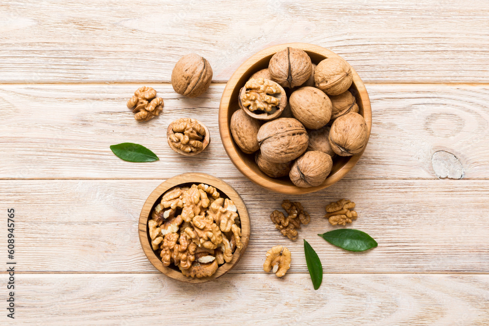 Wall mural walnut kernel halves, in a wooden bowl. close-up, from above on colored background. healthy eating w