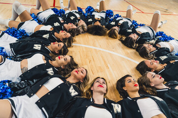 A group of cheerleaders lying on the floor forming a circle with their heads together. High quality...