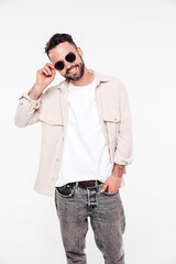 Portrait of handsome smiling stylish hipster lambersexual model. Sexy man dressed in white T-shirt and jeans. Fashion male isolated on white background in studio. In sunglasses
