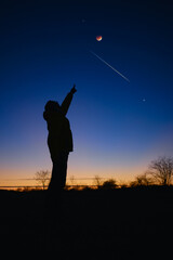 Silhouette of a man with Milky Way starry skies, lunar eclipse and meteor shower.