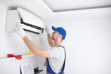 Service guy cleaning and maintaining air condition unit. - obrazy, fototapety, plakaty