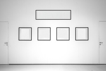 In sala di esposizione dalle pareti bianche sono esposte cornici con l'interno vuoto. L'interno bianco delle cornici permette l'inserimento di immagini o testo. Cornici allineate fra due porte. © massimo_g